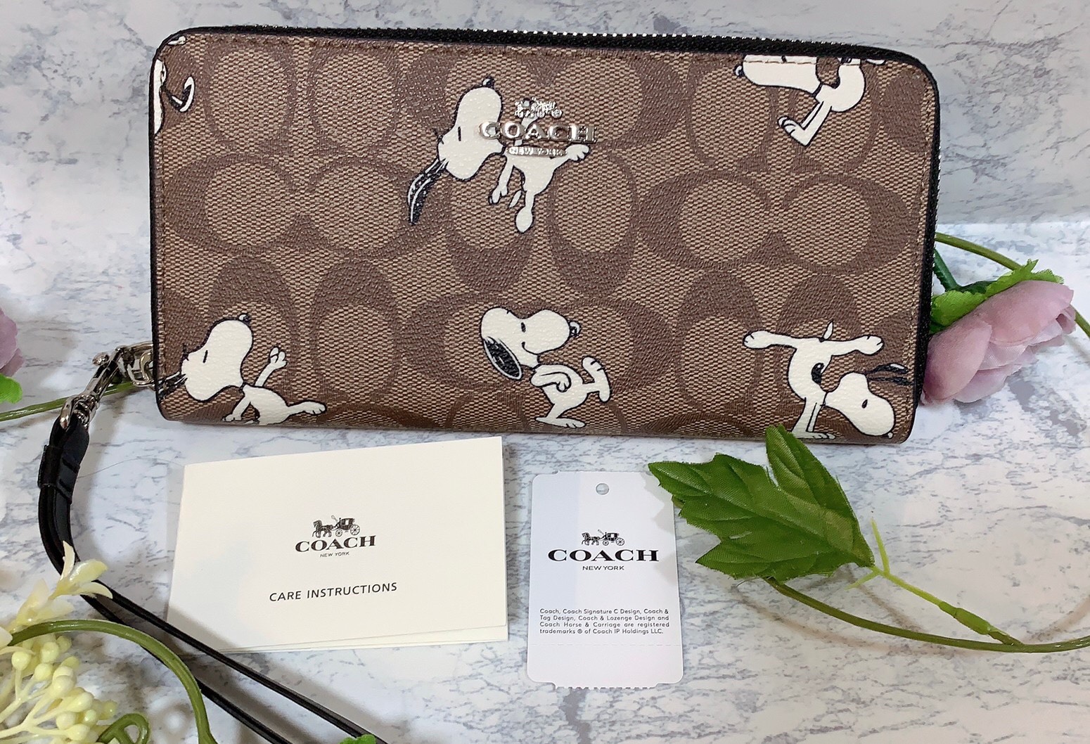 【COACH】スヌーピーのキャラクターが可愛い、付け外し可能なストラップが付いたブラウンの長財布
